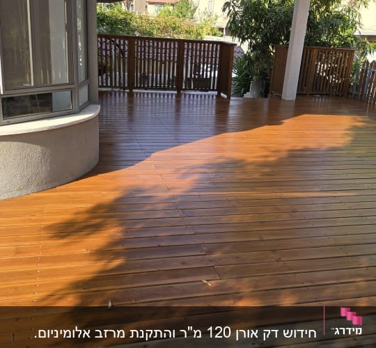דק עץ חום עם גדר עץ וצמחייה מסביב